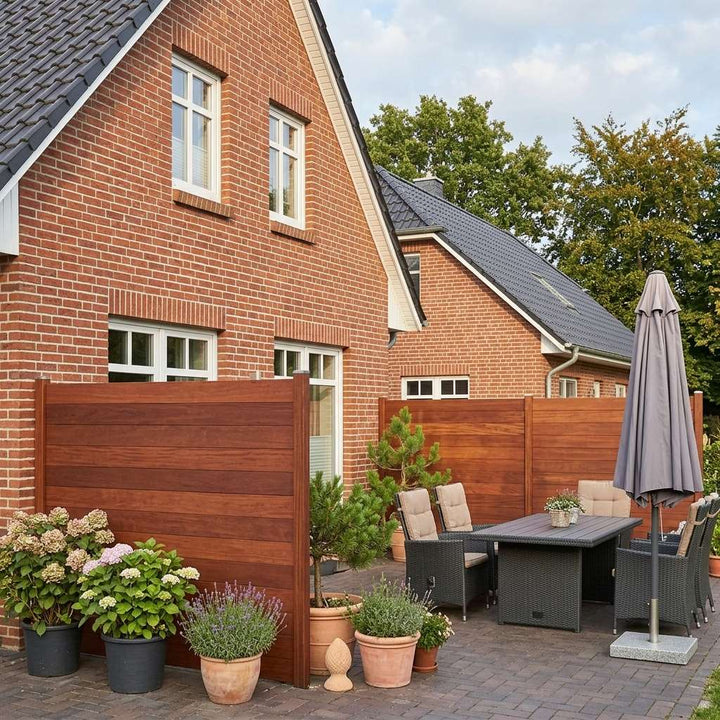 Bambus-Sichtschutzzaun mit horizontalen Lamellen als Abgrenzung einer Terrasse mit Sitzgruppe und Pflanzen.