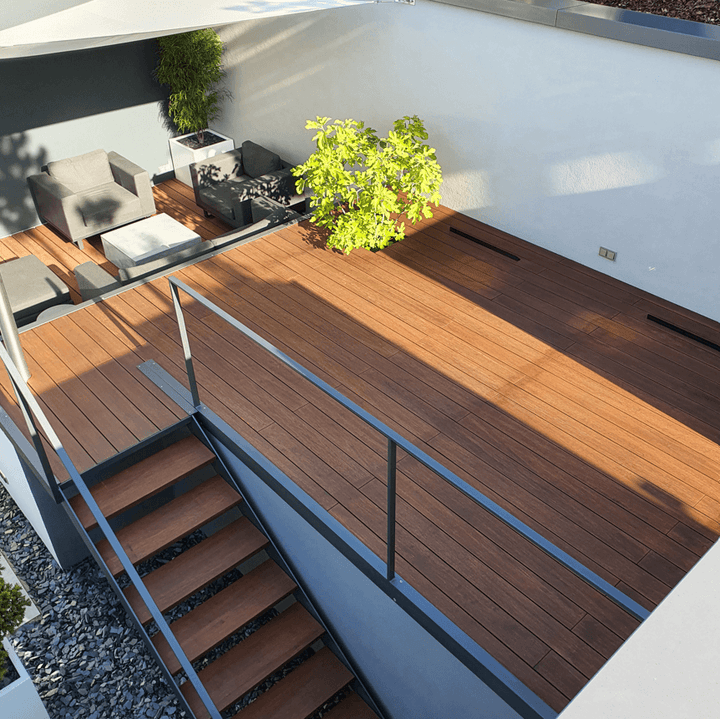 Moderne Dachterrasse mit hochwertigen AMBOOO Bambus-Terrassendielen, stilvollen Gartenmöbeln und grünen Pflanzen. Eine Treppe mit passender Bambus-Beplankung führt zur unteren Etage.