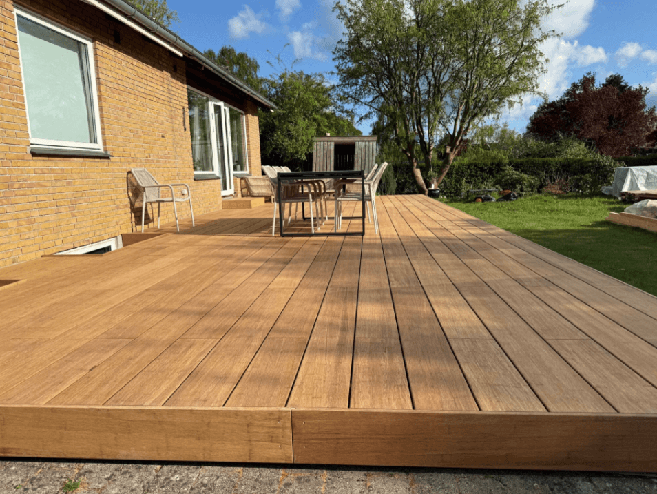 Hochwertige Bambusterrasse mit breiten Terrassendielen, großzügiger Sitzfläche und modernem Design in einem gepflegten Hausgarten. In der Farbe Sand als Komplettpaket mit einer Aluminium Unterkonstruktion.