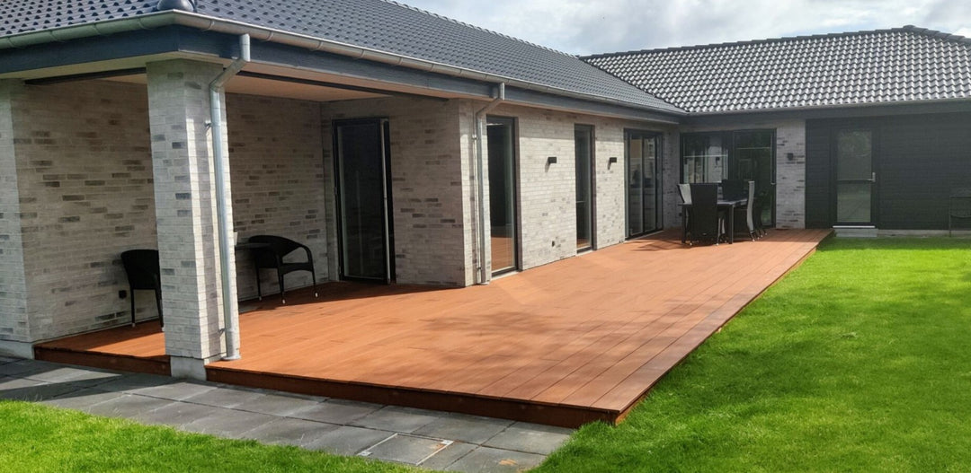 Ein Einfamilienhaus mit vorgelagerte Bambusterrasse, hochwertig verlegt in geradlinigem Muster auf grüner Rasenfläche.