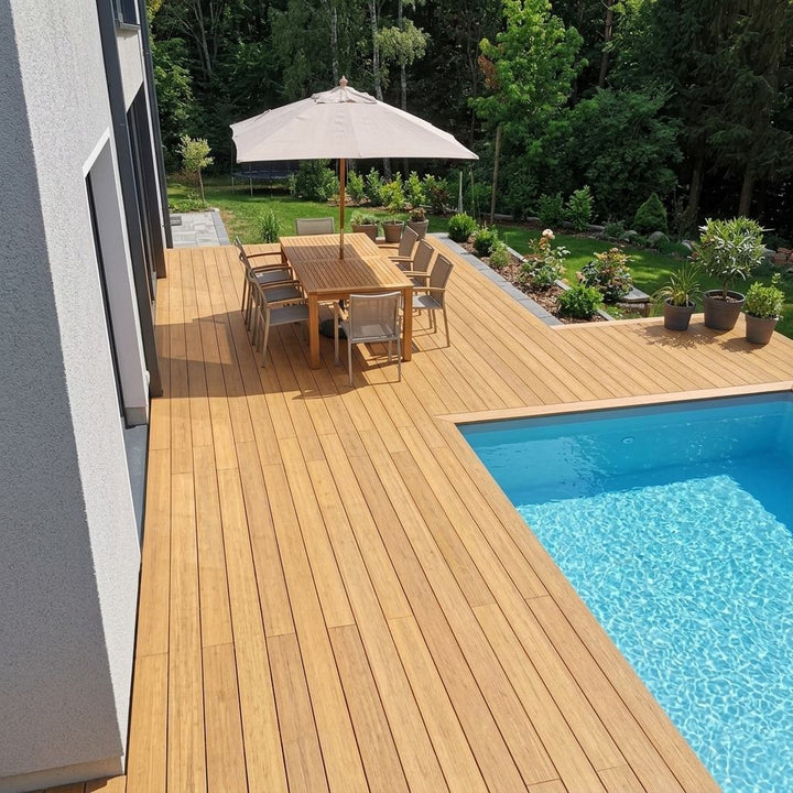 Moderne Poolterrasse aus Colon Closeddecking Terrassendielen mit Essplatz, Sonnenschirm und Blick auf den Garten.
