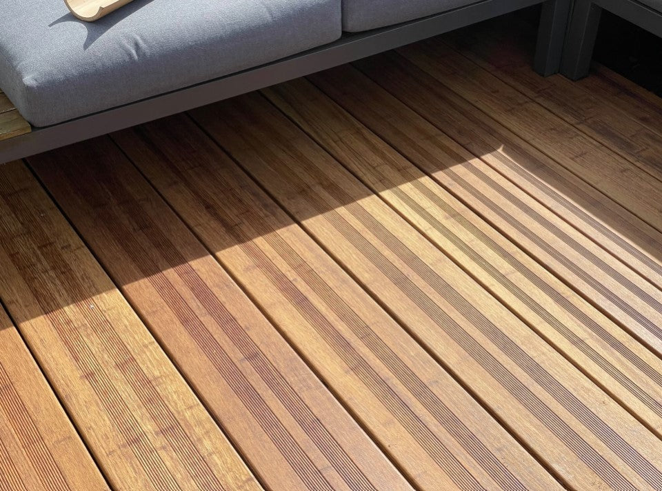 Hochwertige Bambusterrasse mit geriffelten Terrassendielen in der Farbe Sand 20x200x1870 mm und moderner Loungemöblierung. Die warme Holzoptik und das natürliche Lichtspiel unterstreichen die elegante Gestaltung des Außenbereichs.