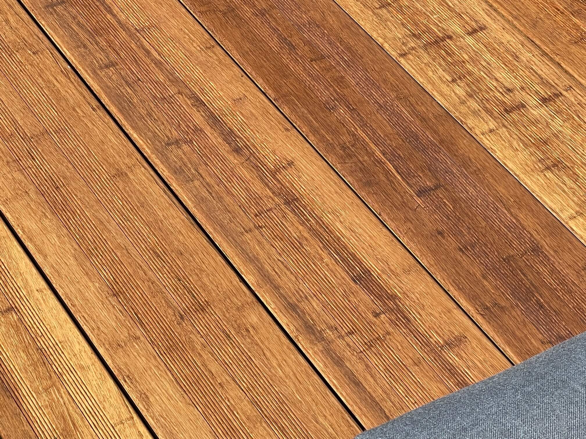 Die Aufnahme zeigt mehrere Terrassendielen in einer warmen, natürlichen Holzoptik. Die Dielen weisen eine realistische Maserung mit unterschiedlichen Braun- und Honigtönen sowie eine fein strukturierte Oberfläche auf. Die gleichmäßigen Fugen zwischen den Dielen unterstreichen das hochwertige Erscheinungsbild und vermitteln den Eindruck einer modernen, pflegeleichten Terrassenlösung.