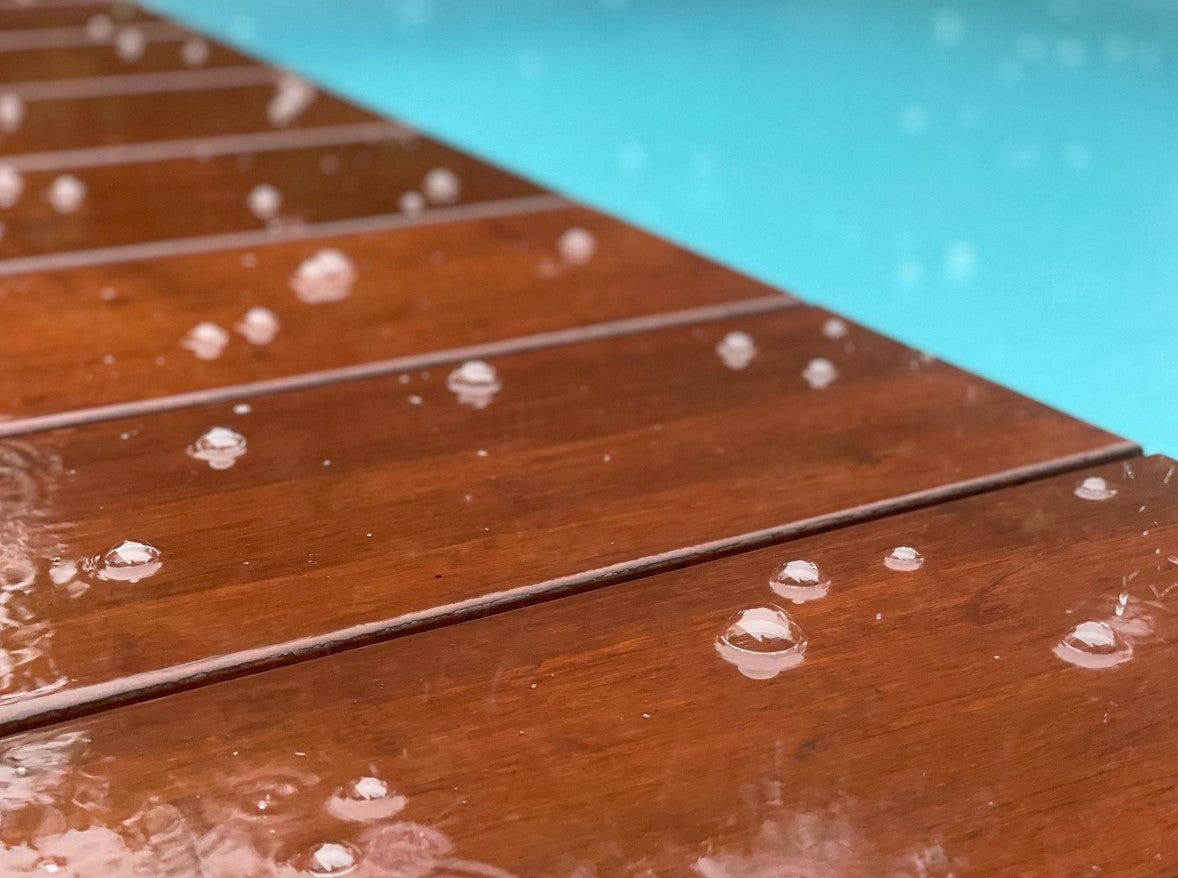 Bambusholz im Regen vor einem Pool