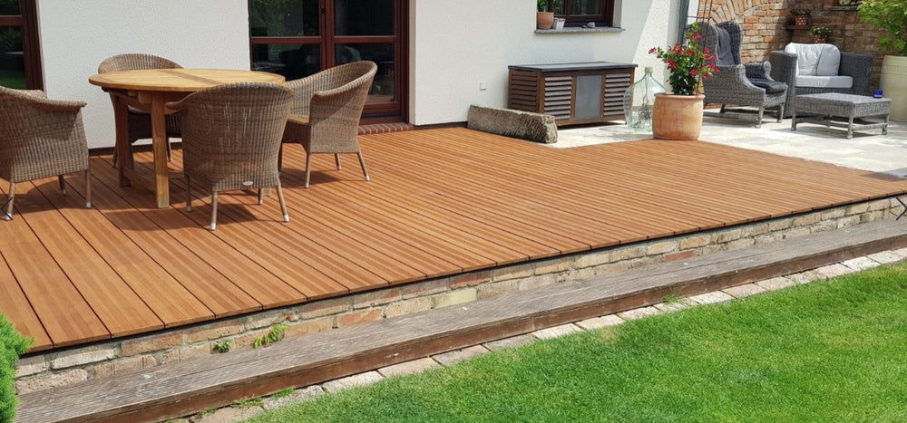 Großzügige Terrasse mit fein geriffelten Bambus-Terrassendielen Vinales, in Kombination mit einer Sitzgruppe und gepflegtem Rasen vor einem Wohnhaus.