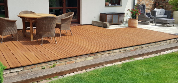 Großzügige Terrasse mit fein geriffelten Bambus-Terrassendielen Vinales, in Kombination mit einer Sitzgruppe und gepflegtem Rasen vor einem Wohnhaus.