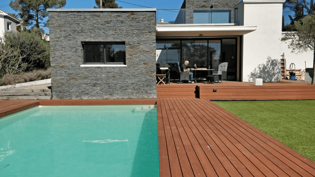 Großzügige Terrasse mit hochwertigen Terrassendielen, integriertem Pool, Sitzlounge und Sonnenschirm in einem gepflegten Garten.