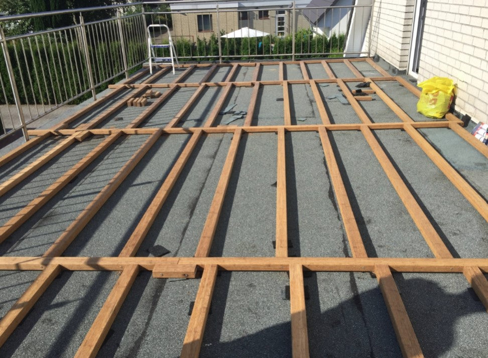 Fachgerecht verlegte Unterkonstruktion aus Bambus für eine Dachterrasse.  Die parallel verlegten Bambus-Tragbalken bilden die stabile Basis für den späteren Terrassenbelag und sind auf einer abgedichteten Dachfläche installiert.