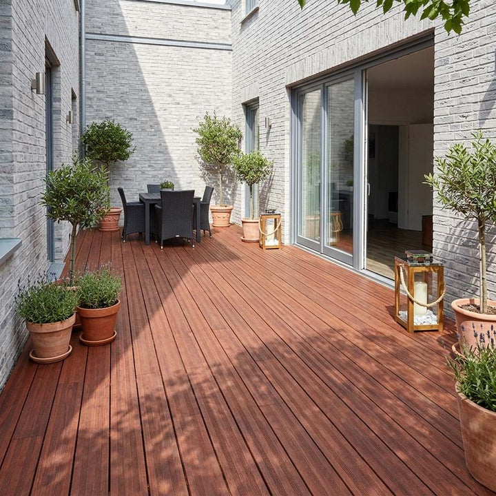 Moderner Balkon mit Terrassendielen in der Farbe coffee, Glasgeländer und Pflanzgefäßen – langlebiger, pflegeleichter Balkon- und Terrassenbelag mit natürlicher Holzoptik.