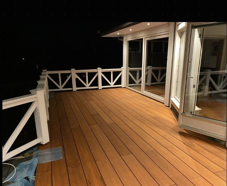 Moderne Terrasse mit glatten Bambus-Terrassendielen und weißem Geländer bei stimmungsvoller 