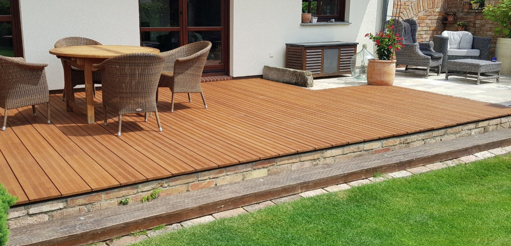Großzügige Terrasse mit fein geriffelten Bambus-Terrassendielen Vinales, Gartenmöbeln und gepflegtem Rasen vor einem Wohnhaus.