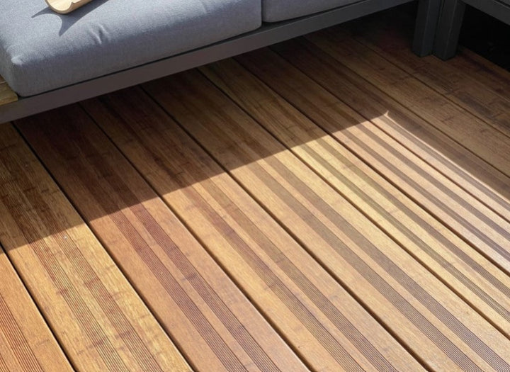 Hochwertige Bambusterrasse mit geriffelten Terrassendielen in der Farbe Sand 20x200x1870 mm und moderner Loungemöblierung. Die warme Holzoptik und das natürliche Lichtspiel unterstreichen die elegante Gestaltung des Außenbereichs.