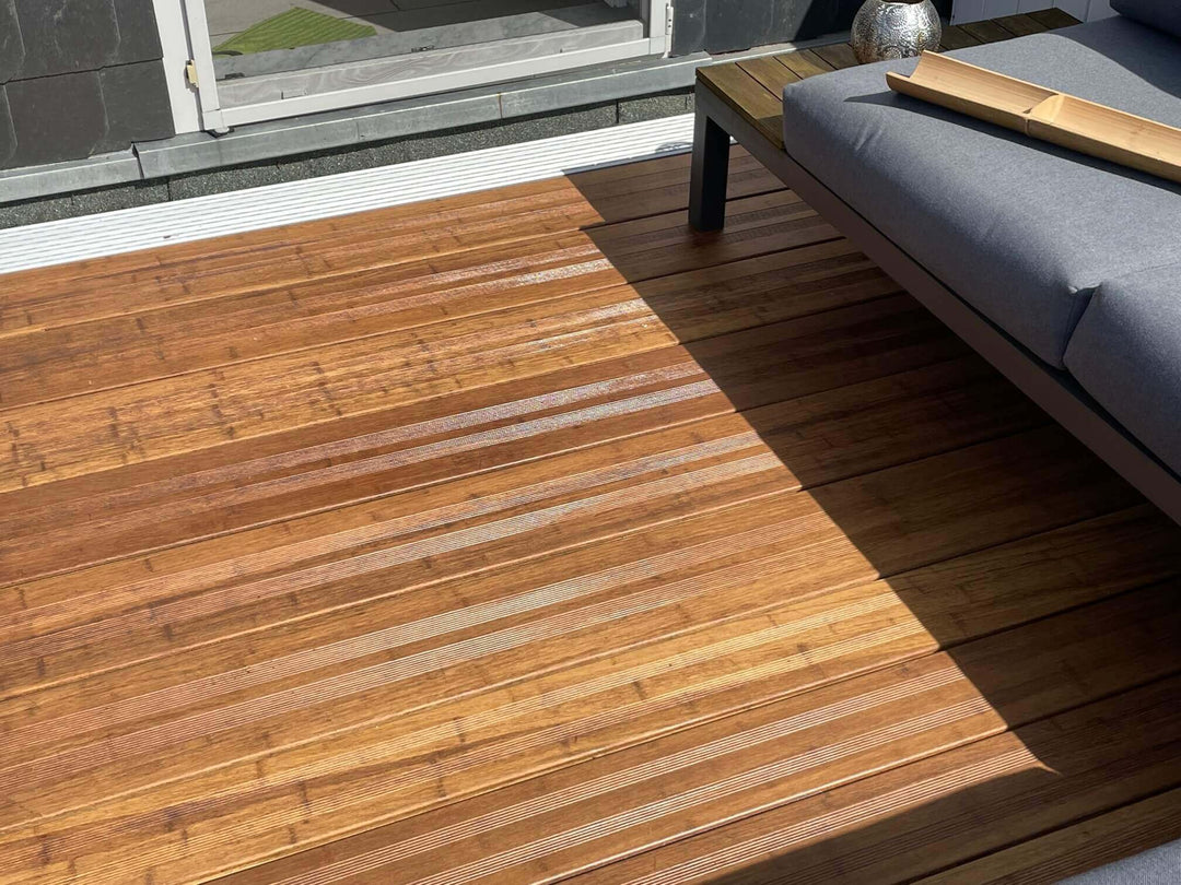 Moderne Bamusterrasse mit hochwertigen, geriffelten AMBOOO Terrassendielen und stilvoller Loungemöblierung. Das natürliche Holzbild, die feine Riffelung und das Spiel von Licht und Schatten schaffen eine elegante Atmosphäre im Außenbereich.