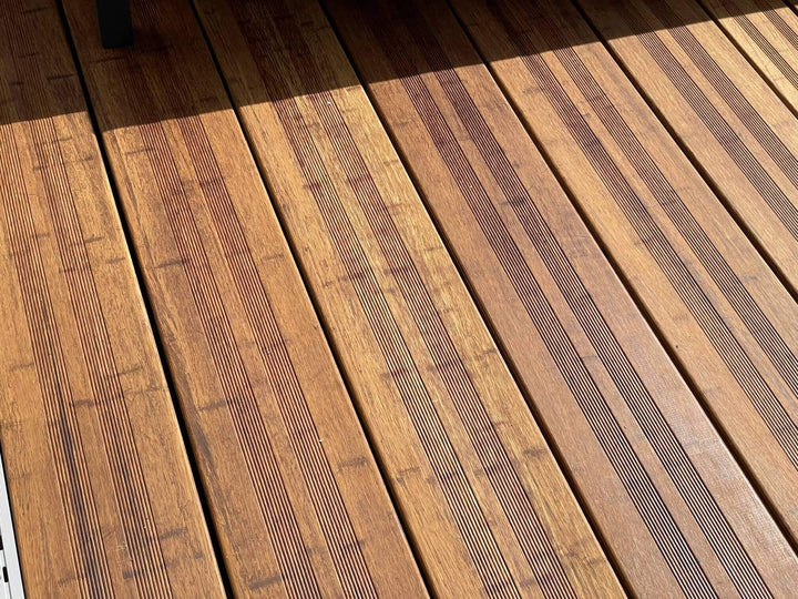 Hochwertige Bambusterrasse mit geriffelten Terrassendielen in der Farbe Sand 20x200x1870 mm und moderner Loungemöblierung. Die warme Holzoptik und das natürliche Lichtspiel unterstreichen die elegante Gestaltung des Außenbereichs