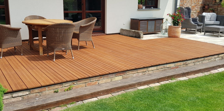 Großzügige Terrasse mit fein geriffelten Bambus-Terrassendielen Vinales, in Kombination mit einer Sitzgruppe und gepflegtem Rasen vor einem Wohnhaus.