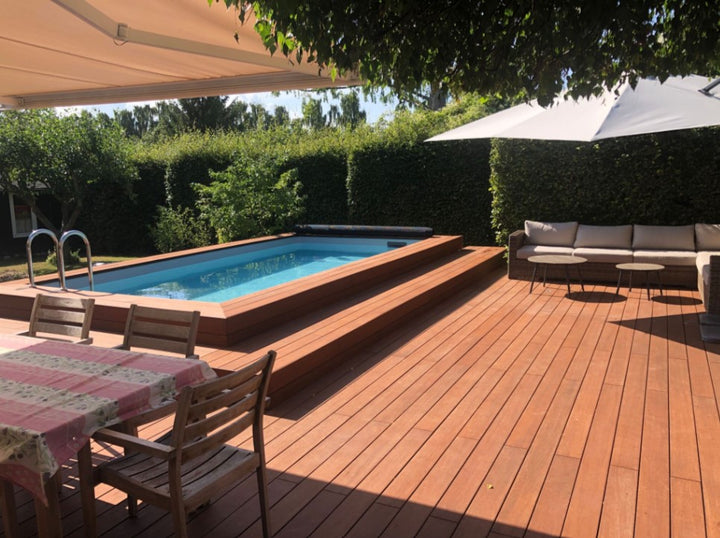 Großzügige Poolterrasse mit eingelassenem Swimmingpool, gemütlicher Lounge, Sonnenschirm und Essbereich in einem gepflegten Garten.
