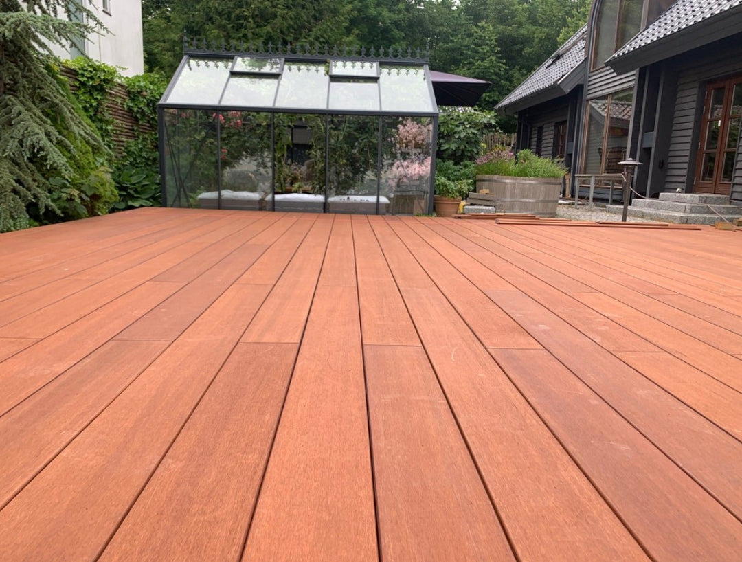 Große Terrasse im Bau vor einem modernen Einfamilienhaus mit Wintergarten und Solaranlage auf dem Dach. 
